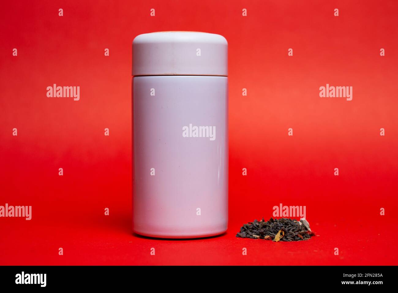 thermos bianchi con tè verde su sfondo rosso. Foto Stock