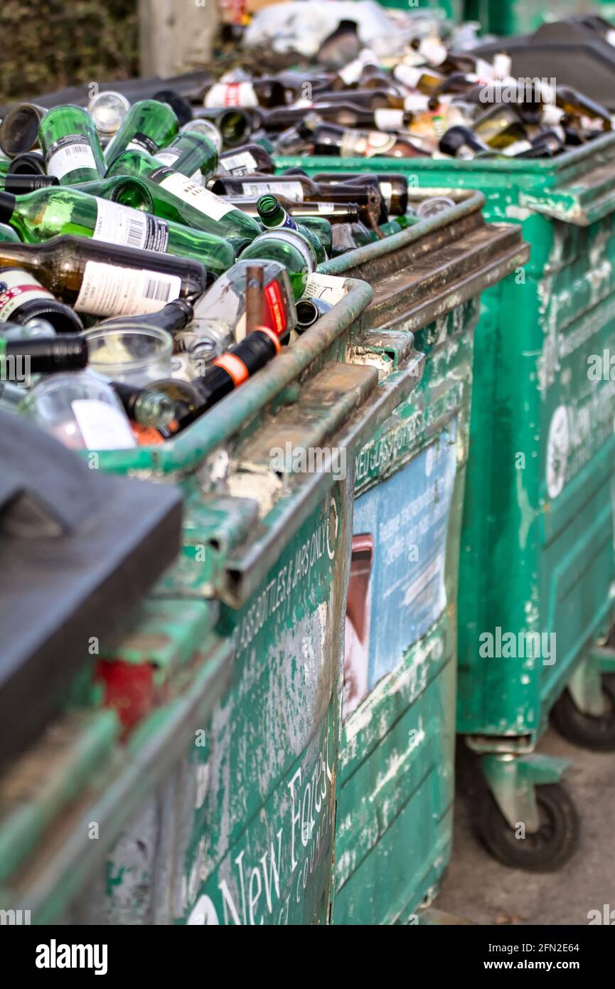 Contenitori di riciclaggio vecchio metallo con batteria pieni di vetro verde e. Bottiglie marroni in attesa di raccolta per il riciclaggio UK Foto Stock