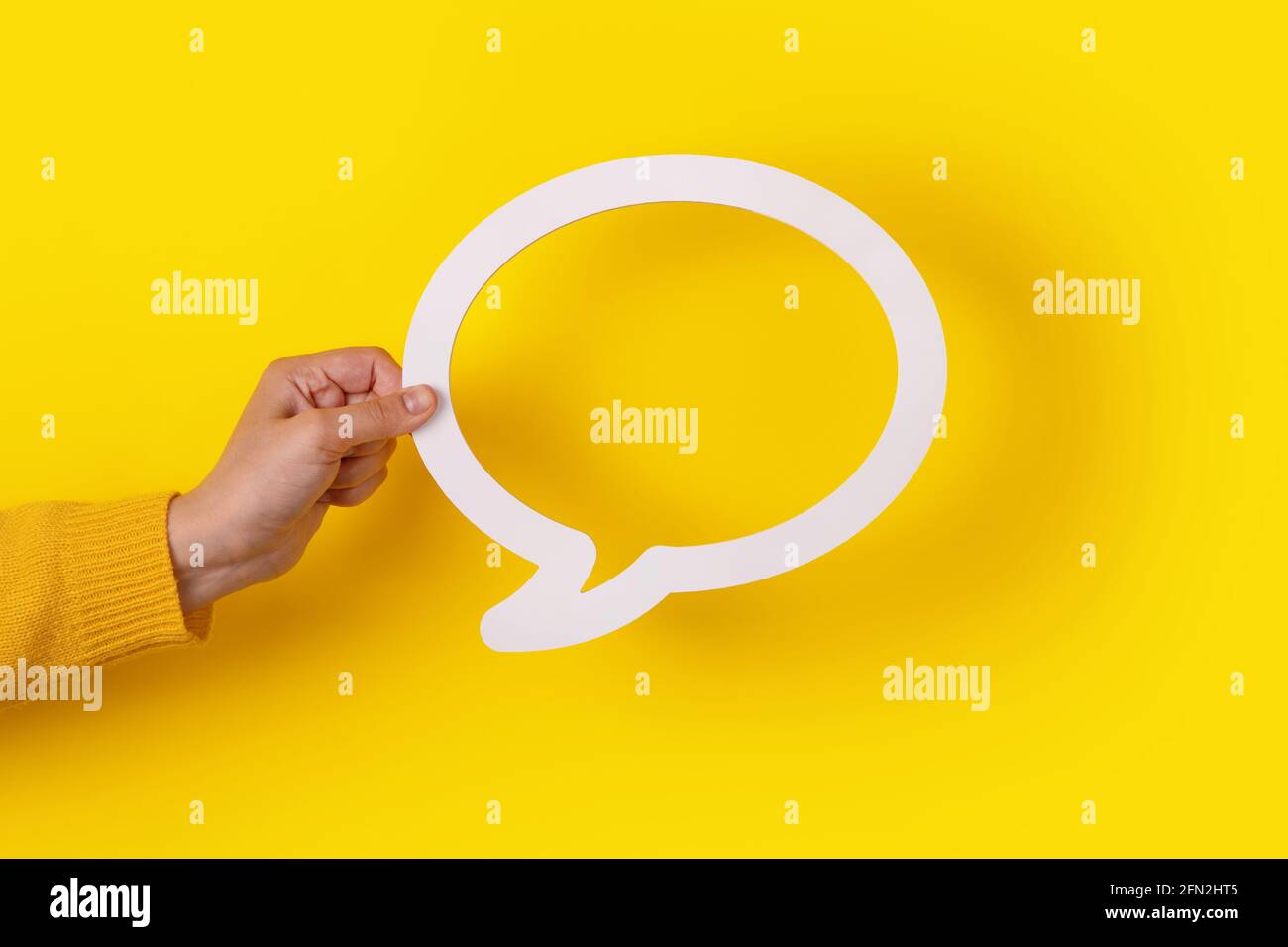 Bolla di dialogo in mano su sfondo giallo Foto Stock