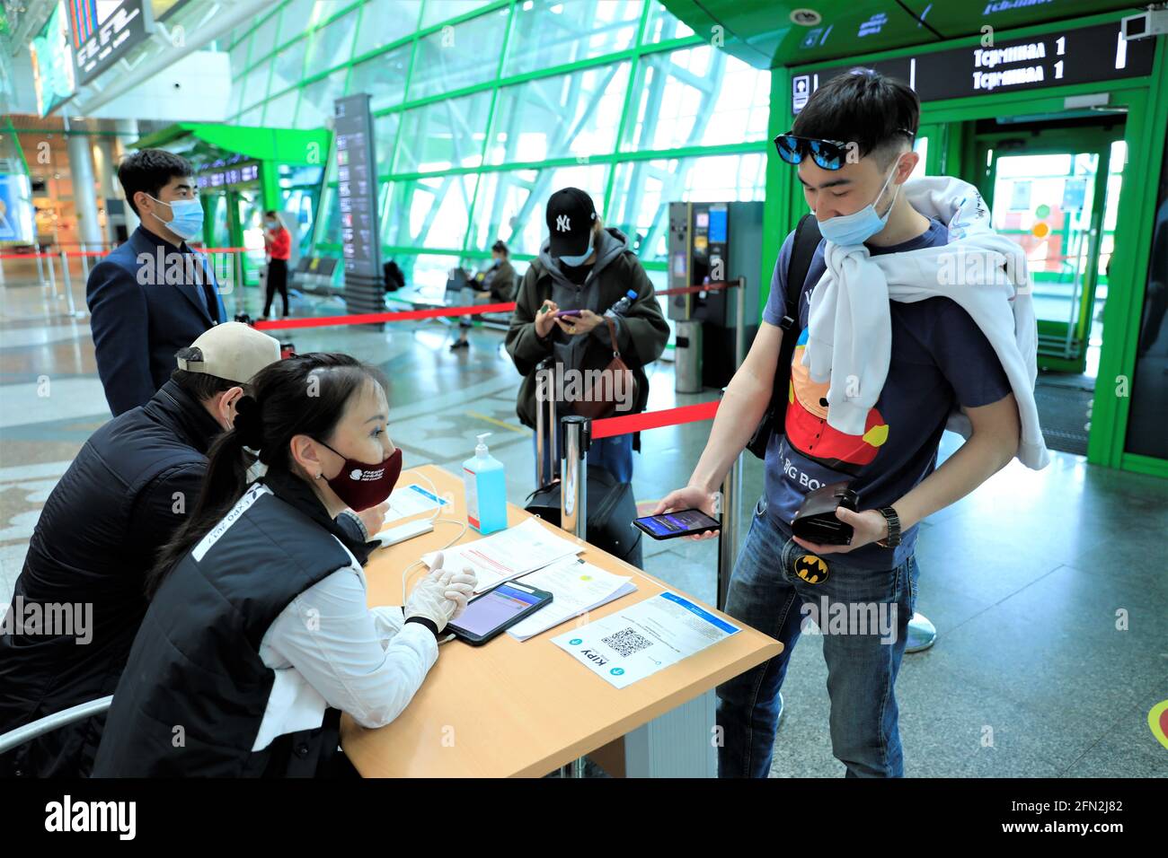 (210513) -- NUR-SULTAN, 13 maggio 2021 (Xinhua) -- le persone scansionano il codice QR per identificare lo stato di salute nell'aeroporto di Nur-Sultan, Kazakhstan, 13 maggio 2021. Il Comitato per il controllo epidemiologico sanitario del Kazakistan ha annunciato che l'aeroporto di Nur-Sultan è destinato a lanciare un progetto pilota Ashyq per identificare lo status COVID-19 dei passeggeri a partire dal maggio 12. I passeggeri dovranno sottoporre a scansione i propri codici QR per identificare lo stato COVID-19 in base ai dati provenienti dal sito di integrazione unico dei test PCR e dal centro di controllo COVID-19 del Ministero della Salute prima di entrare nell'aeroporto di Nur-Sultan. In rosso Foto Stock