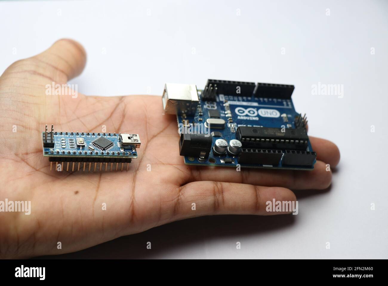 Arduino uno e arduino nano sono tenuti in mano. Schede Arduino utilizzate per realizzare progetti creativi arduino e per l'istruzione Foto Stock