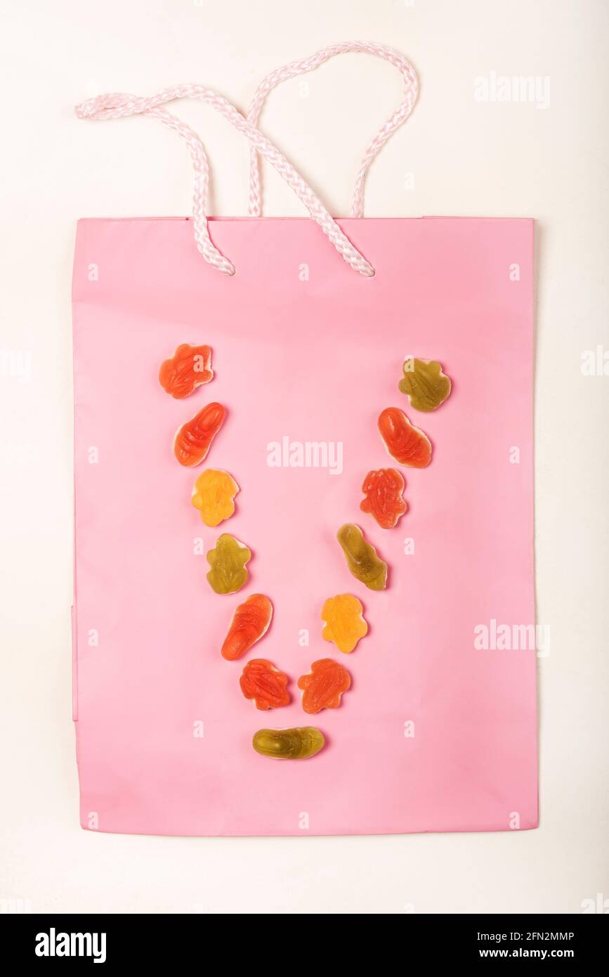 Lettere alfabetiche colorate realizzate con una disposizione di dolci  (caramelle) su una borsa regalo rosa, su sfondo bianco.V Foto stock - Alamy
