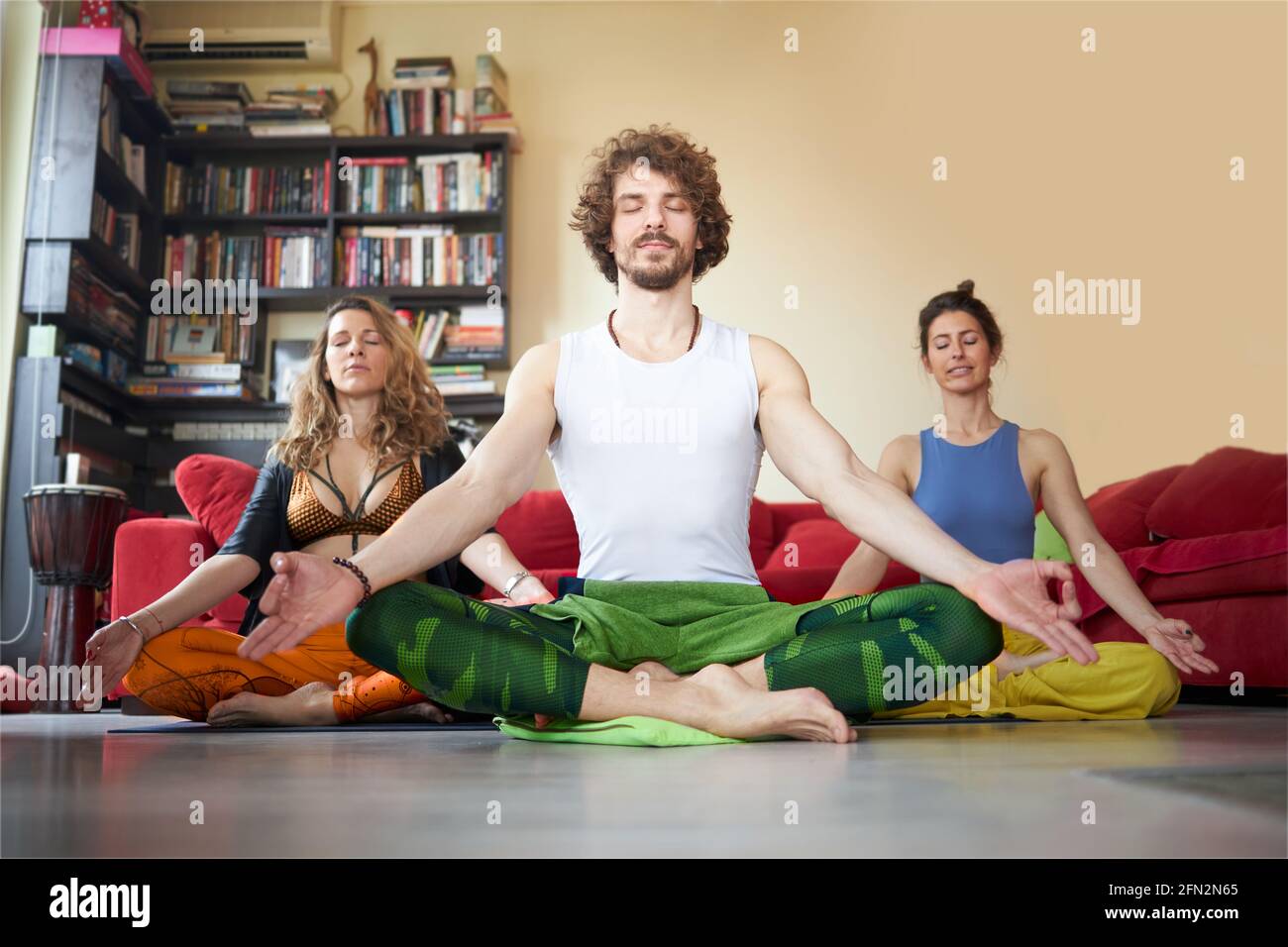 Tre amici che meditano nel loro appartamento Foto Stock