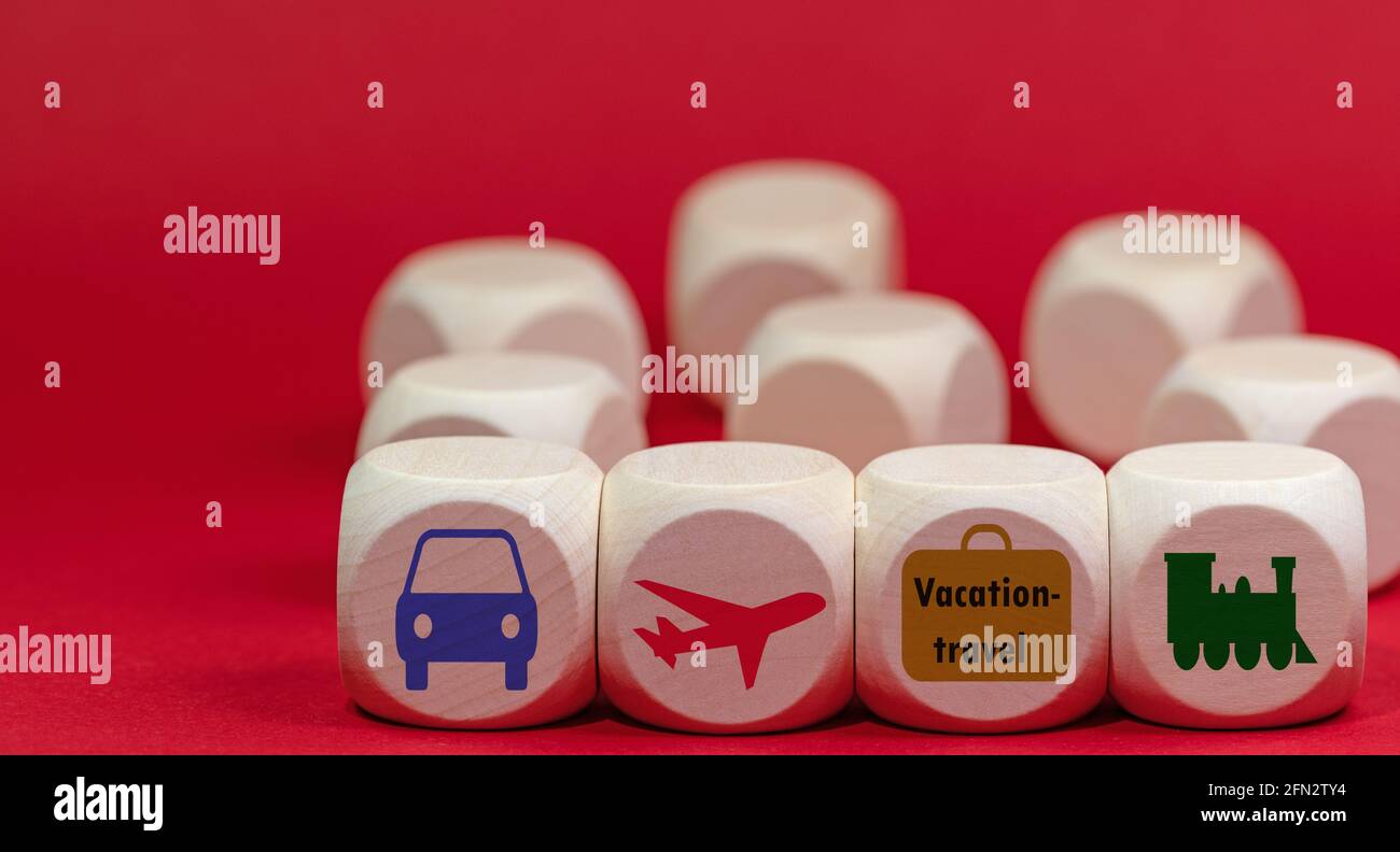 Simboli per viaggi di vacanza su cubi di legno contro un rosso sfondo Foto Stock