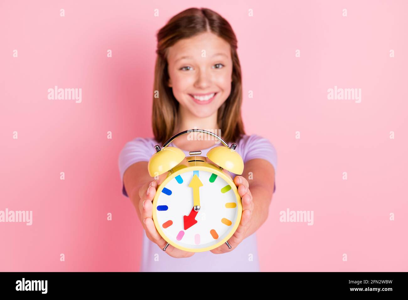 Foto di allegra bella ragazza tenere sveglia show il tempo è isolato su  sfondo di colore rosa pastello Foto stock - Alamy