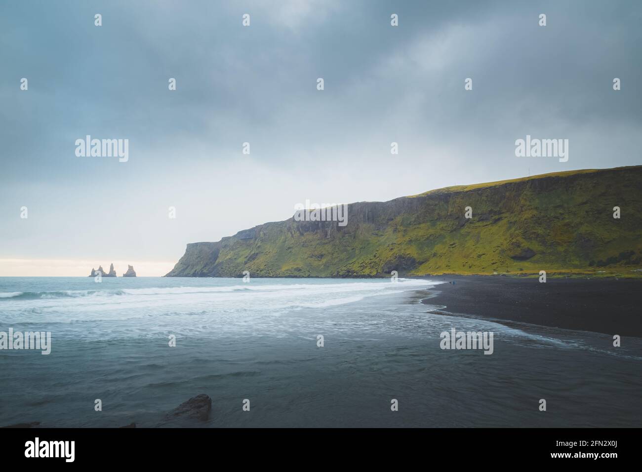Moody, suggestivo paesaggio marino di Reynisdrangar stack di mare a Reynisfjara spiaggia di sabbia nera nel villaggio costiero di pescatori di Vik nel sud IC Foto Stock
