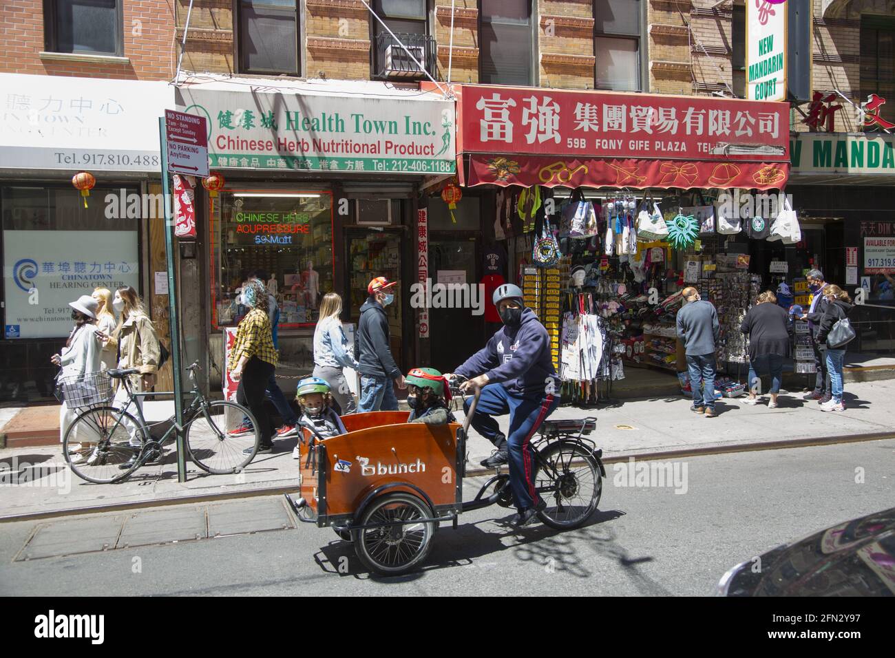 Padre corre una bici da carico con i bambini in mano lungo Mott Street a Chinatown, Manhattan, New York City. Foto Stock