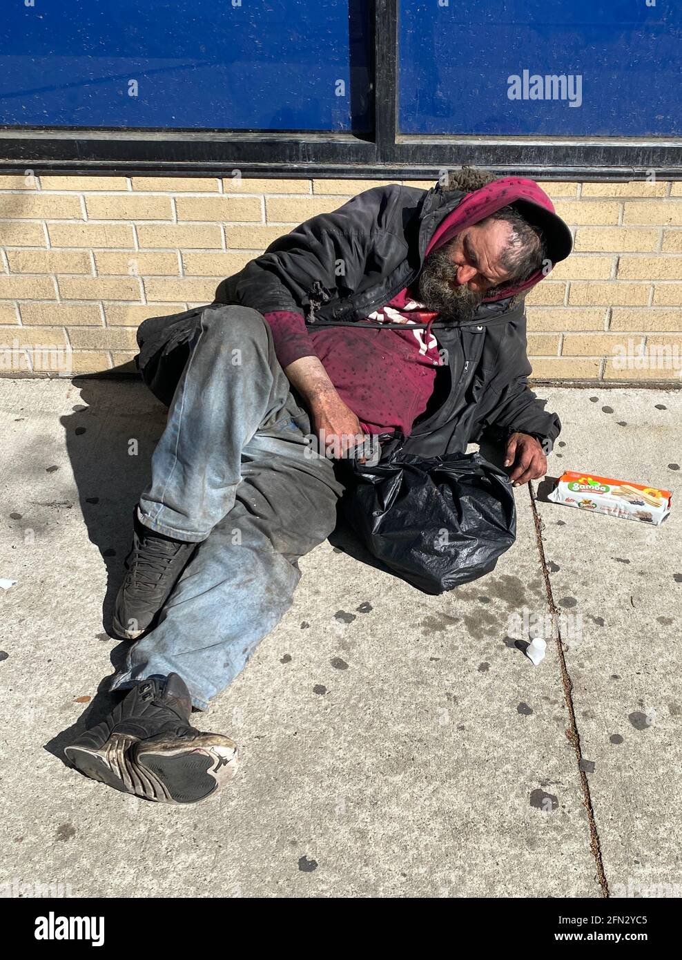 L'uomo sporco e disonirato dorme per strada, un'altra vittima di alcol che avvelenano corpo e mente. Brooklyn, New York. Foto Stock