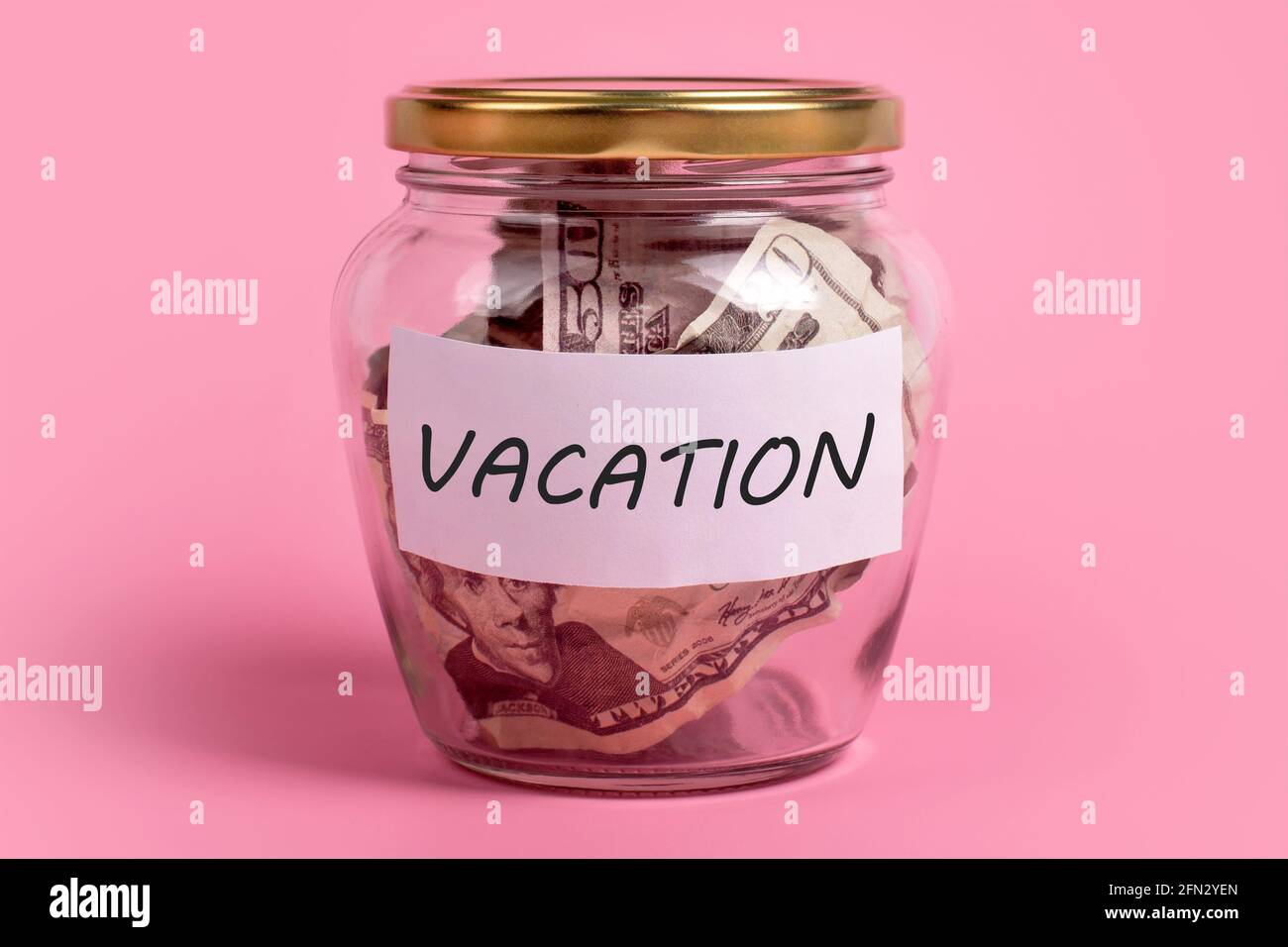 Concetto di budget per le vacanze. Scatola di soldi con VACANZA di parola su carta adesiva della nota. Dollari in vetro vaso di denaro con etichetta di risparmio, finanziario, risparmio. Vaso pieno Foto Stock