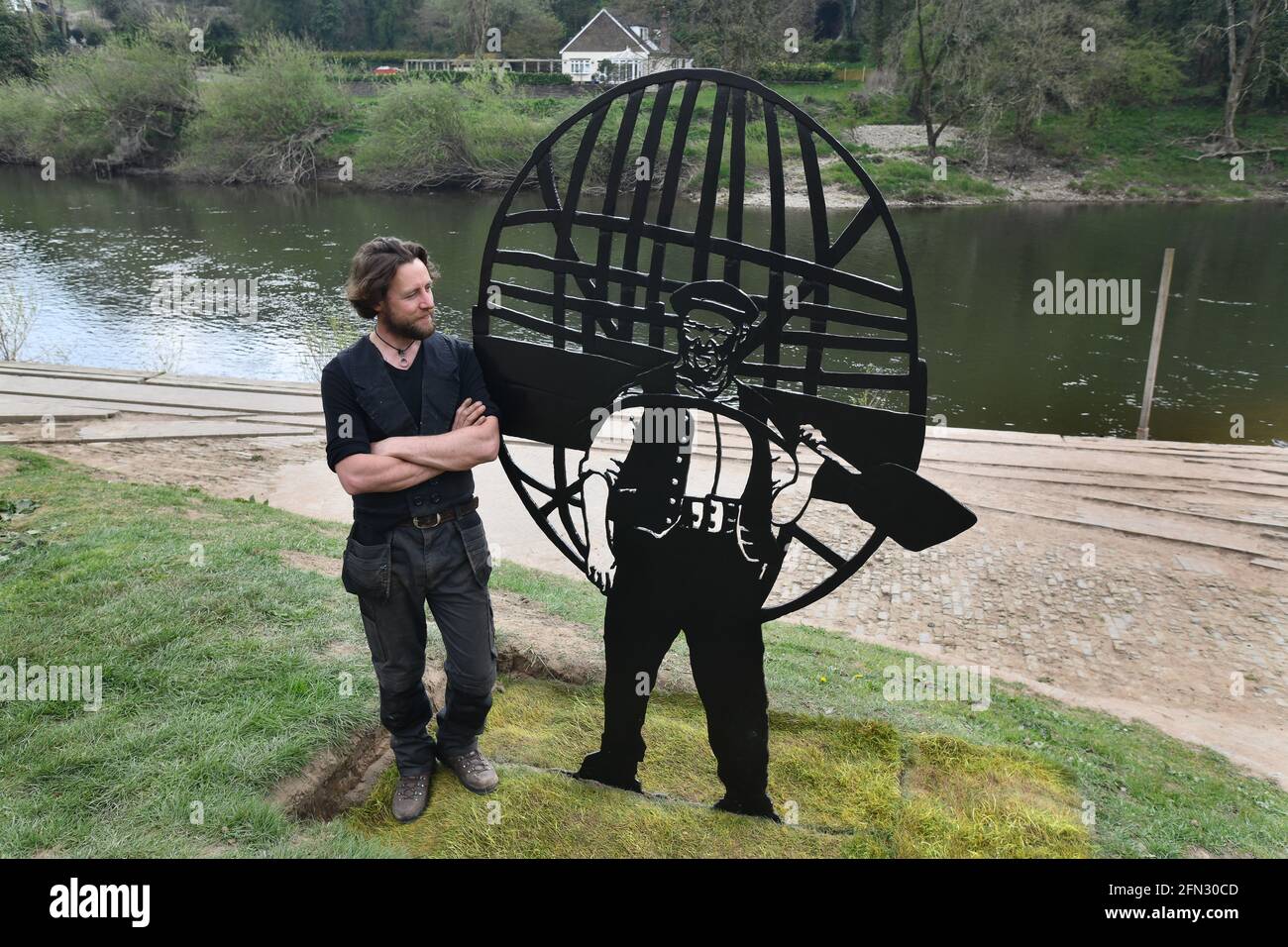 La scultura in ferro di Ironbridge Coracle uomo Tommy Rogers con Lo scultore Luke Perry accanto al fiume Severn, ritratto da DAVID BAGNALL Foto Stock
