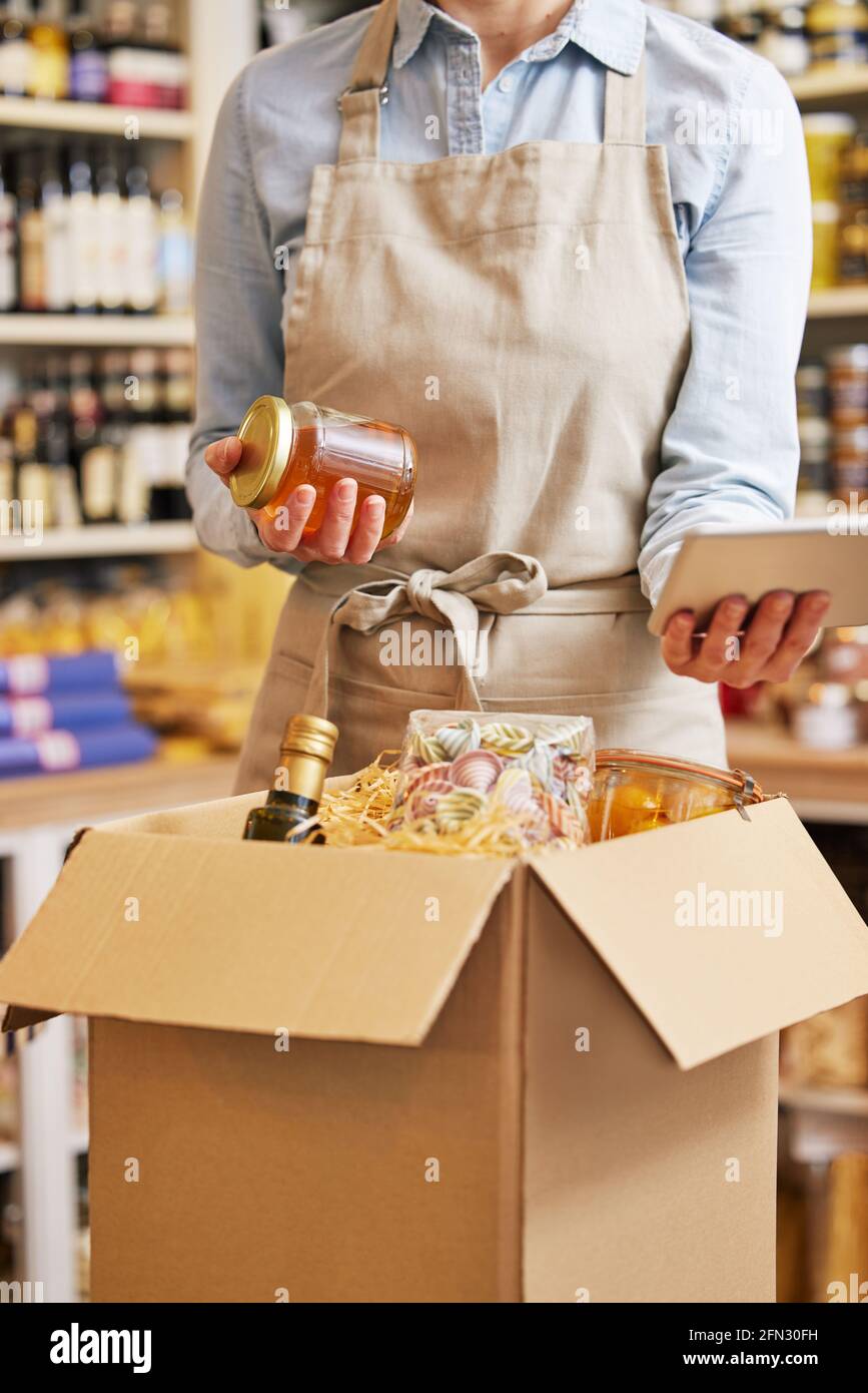 Primo piano del proprietario femminile di Delicatessen Food Shop con Tavoletta digitale preparazione ordine di alimentari online Foto Stock