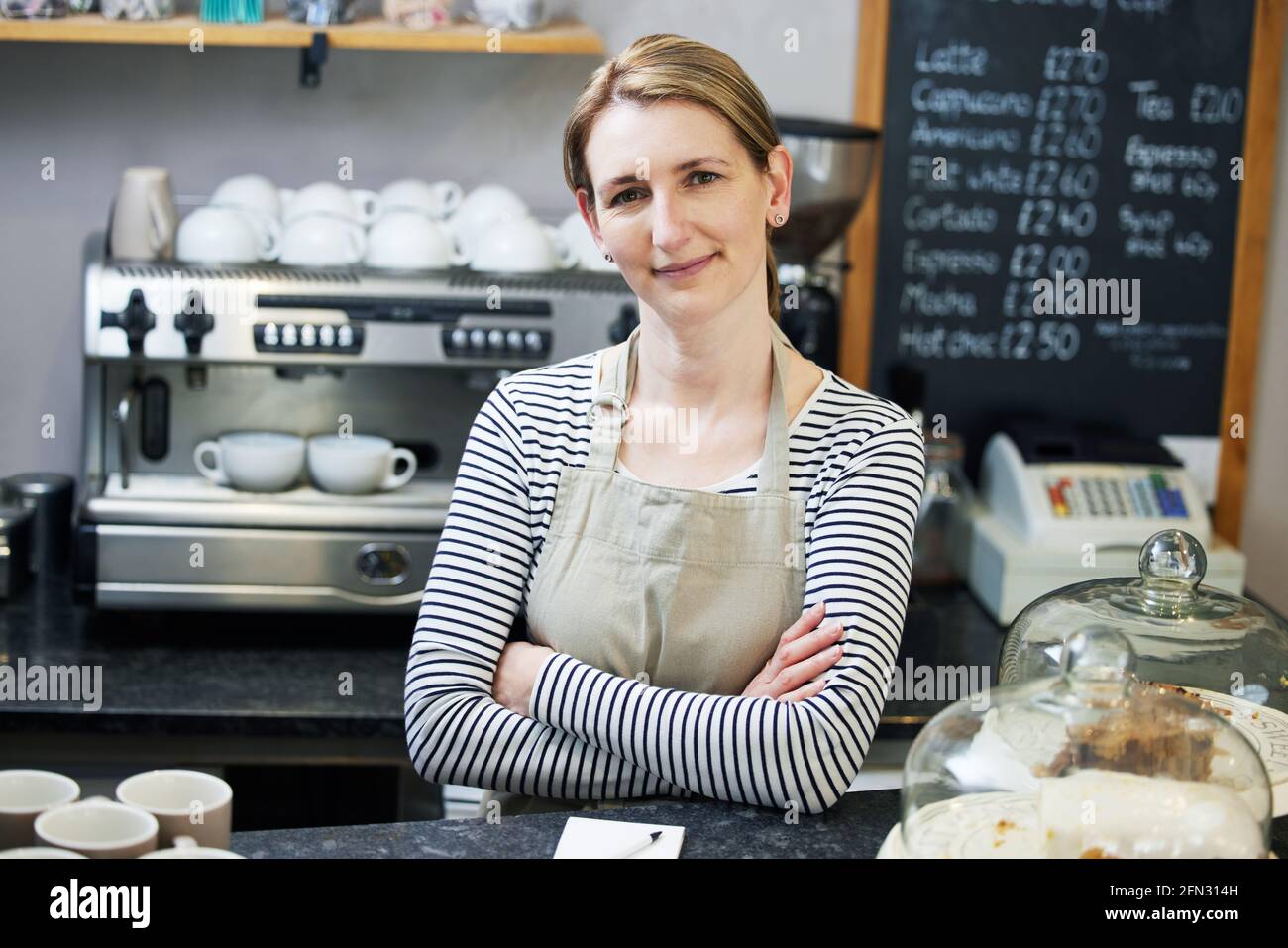 Ritratto del proprietario femminile che si trova all'interno di una caffetteria locale indipendente O Cafe Foto Stock