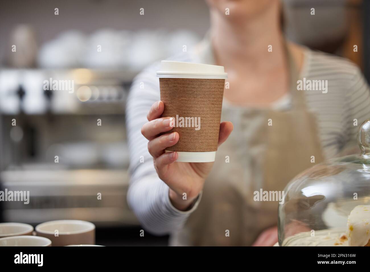 Primo piano di Female Worker in Cafe che serve caffè in Tazza riciclabile sostenibile Foto Stock
