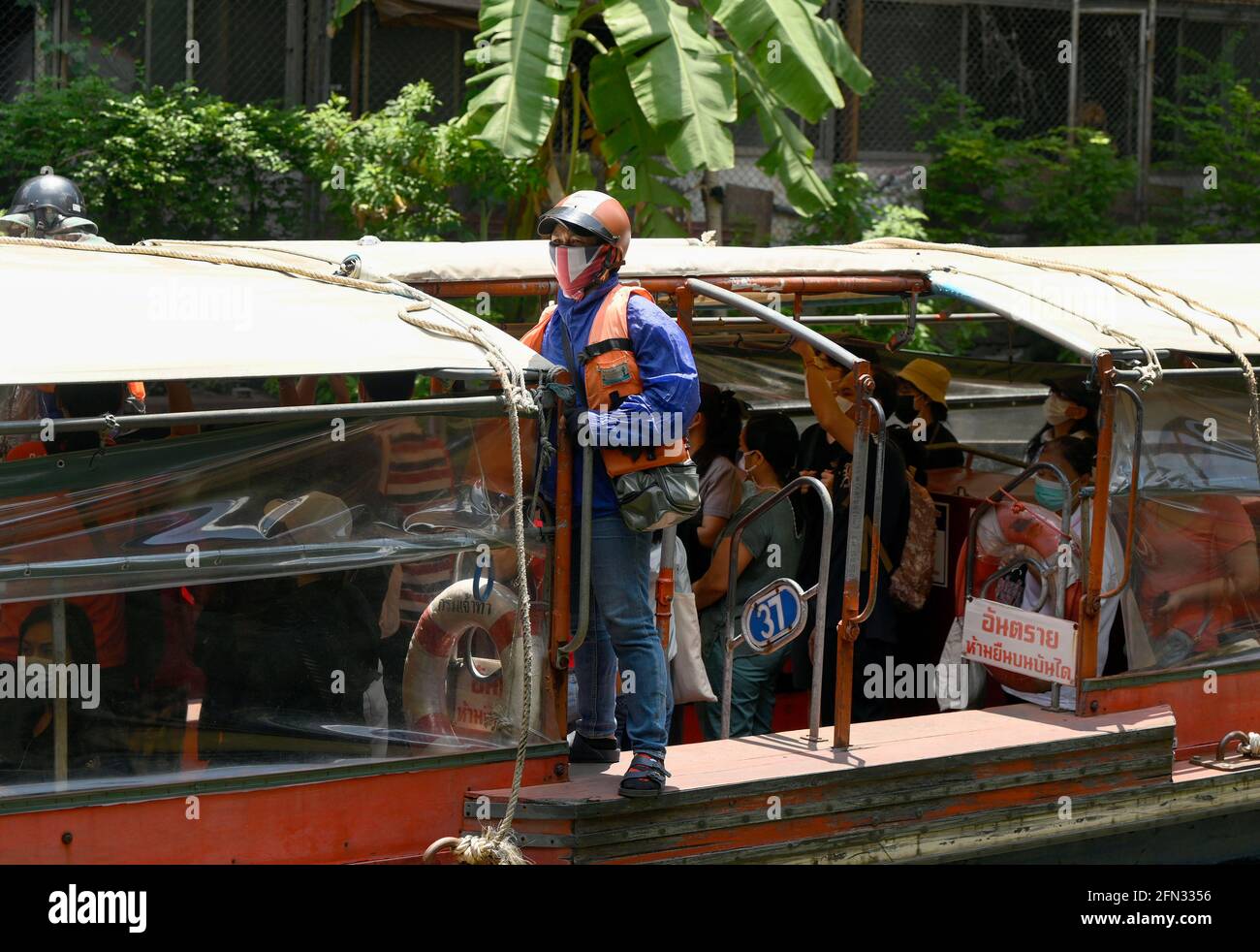 Bangkok, Thailandia. 13 maggio 2021. Un ragazzo di barca thailandese che indossa una maschera su una barca espressa in un canale. Il sistema di trasporto pubblico del canale acquatico Saen Saep della città interna di Bangkok porta i pendolari su un canale (khlong) lungo un percorso di 18 km utilizzando un servizio di motoscafo espresso - ha 27 fermate del molo, 100 barche da 40-50 posti, che operano giornalmente dalle 5:30 alle 20:30. Credit: SOPA Images Limited/Alamy Live News Foto Stock