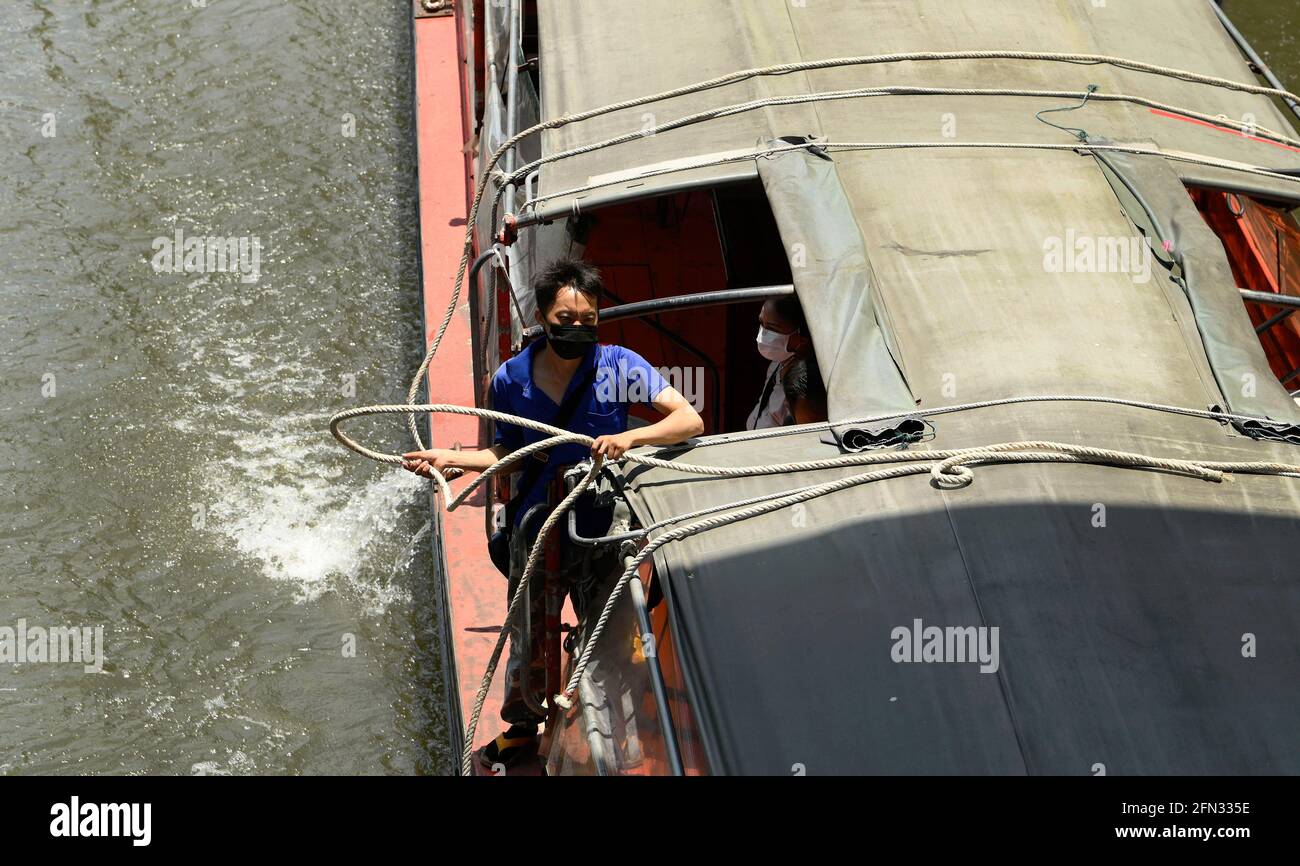 Bangkok, Thailandia. 13 maggio 2021. Un ragazzo di barca thailandese che indossa una maschera su una barca espressa in un canale. Il sistema di trasporto pubblico del canale acquatico Saen Saep della città interna di Bangkok porta pendolari su un canale (khlong) lungo un percorso di 18 km utilizzando un servizio di barca veloce a motore - ha 27 fermate del molo, 100 barche da 40-50 posti, che operano giornalmente dalle 5:30 alle 20:30. Credit: SOPA Images Limited/Alamy Live News Foto Stock