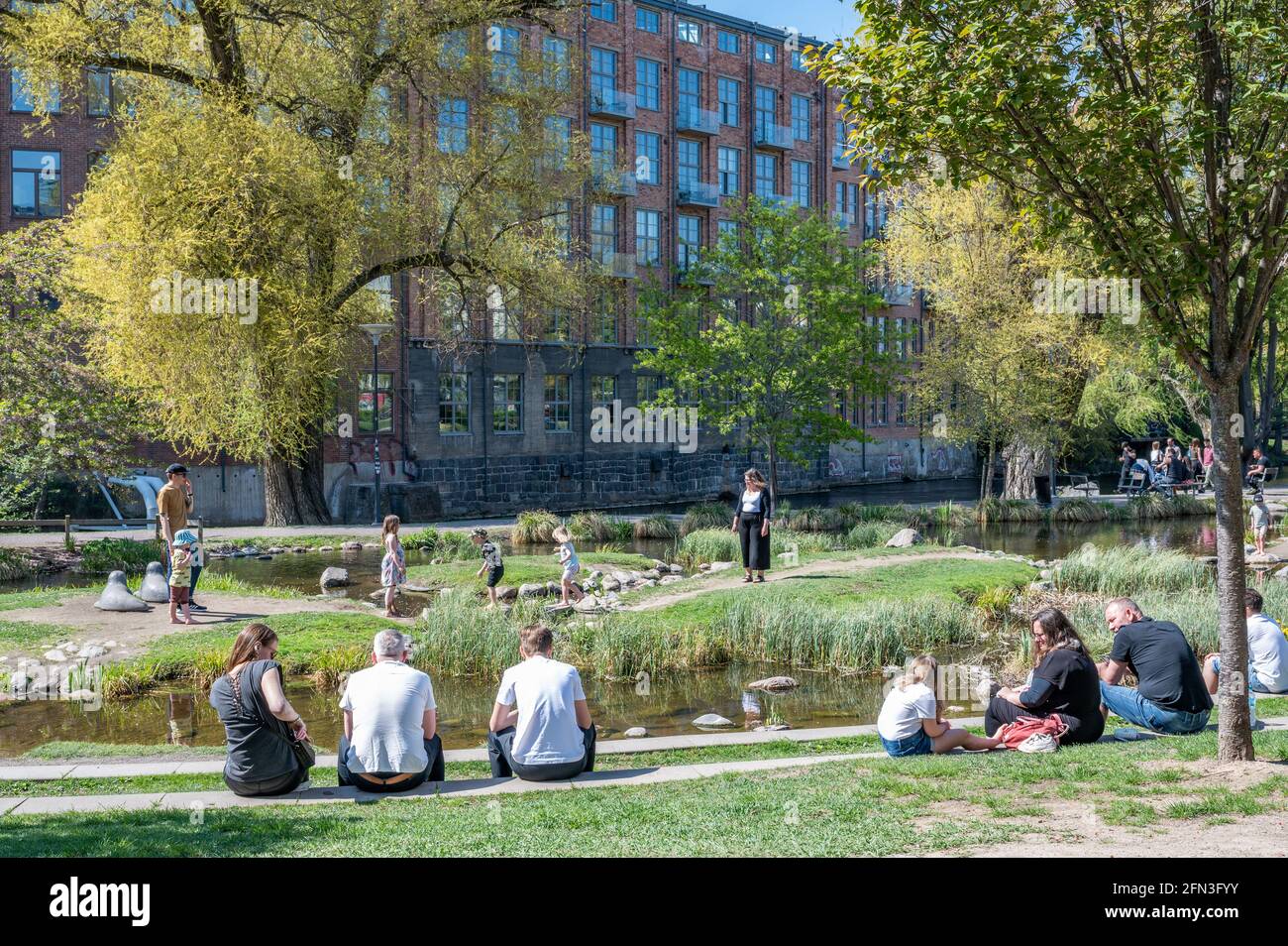 La gente gode di una soleggiata giornata primaverile nel parco cittadino di Strömparken, Norrköping in Svezia Foto Stock