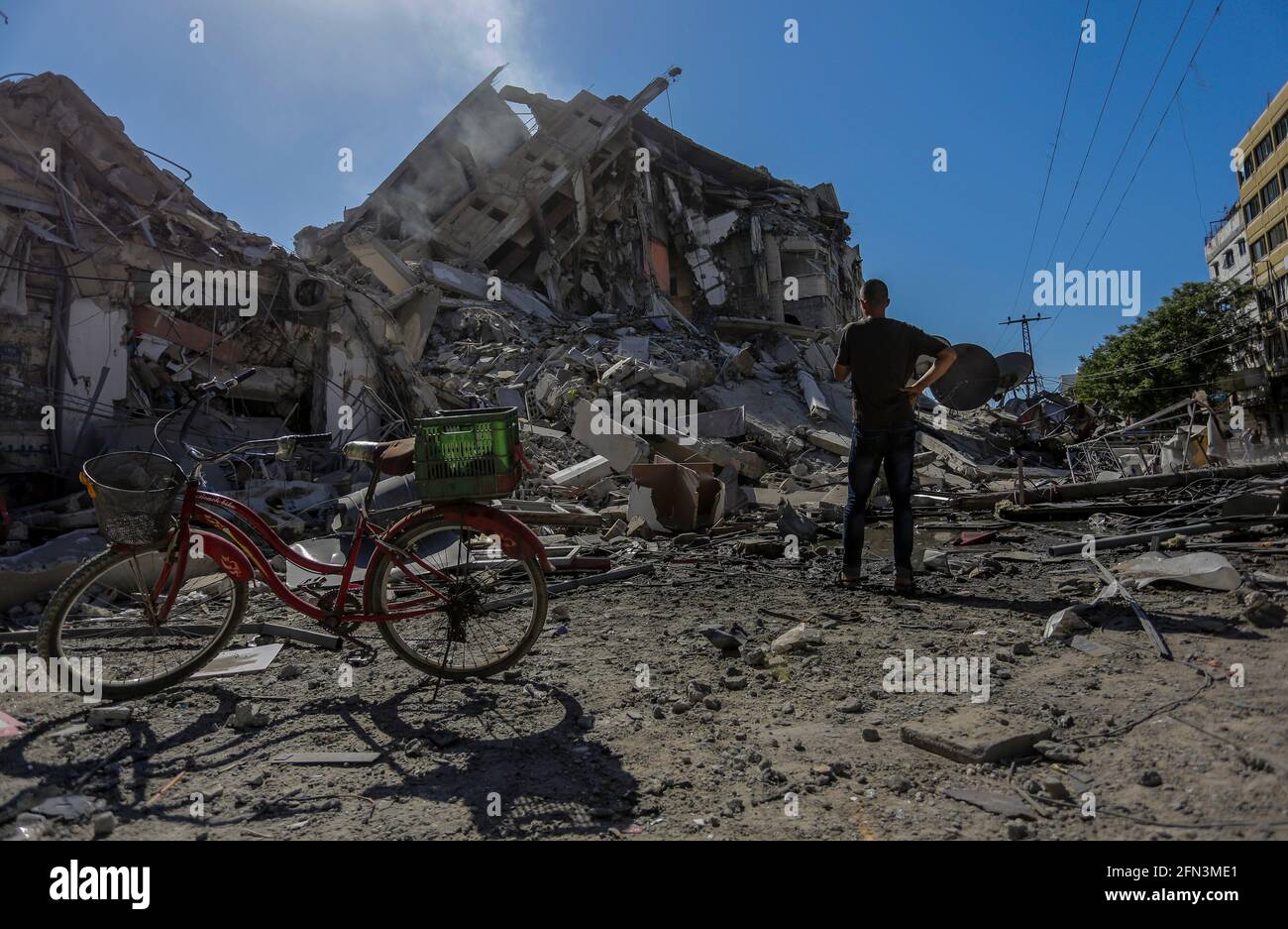 13 maggio 2021, Città di Gaza, striscia di Gaza, Palestina: I palestinesi ispezionano le macerie della torre distrutta di al-Shorouq dopo uno sciopero israeliano a Gaza. In risposta a giorni di violenti scontri tra le forze di sicurezza israeliane e i palestinesi a Gerusalemme, diverse fazioni militanti palestinesi a Gaza hanno lanciato attacchi a razzo dal 10 maggio che hanno ucciso almeno sette israeliani fino ad oggi. Il ministero della salute della striscia di Gaza ha affermato che almeno 109 palestinesi, tra cui 28 bambini, sono stati uccisi durante i recenti rappresaglie israeliane. (Credit Image: © Mahmoud Issa/Quds Net News via ZUMA Wire) Foto Stock