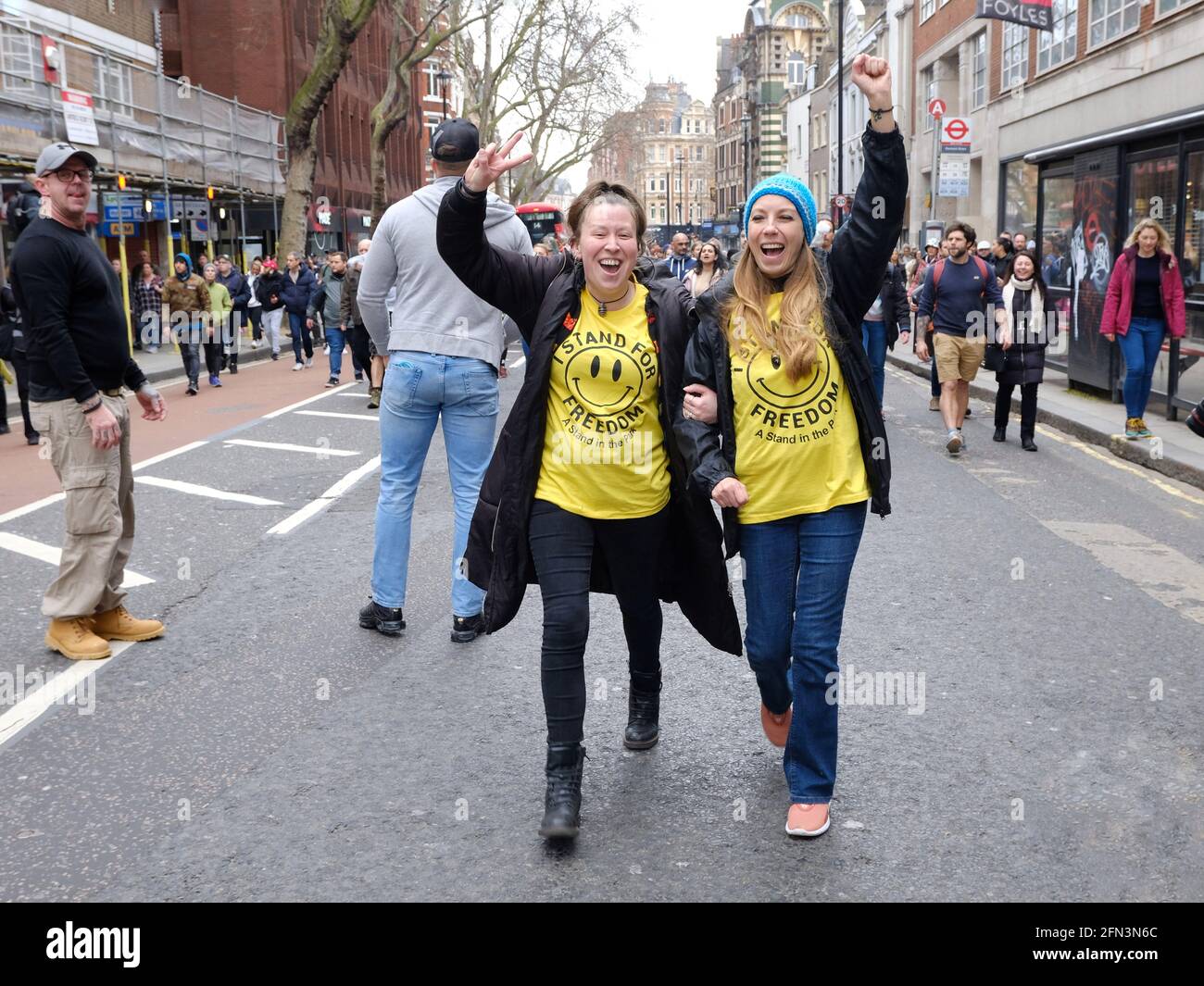 Due manifestanti anti anti anti-lockdown che indossano t-shirt con volti sorridenti, associati alla cultura rave ora adottata sotto questo movimento Foto Stock