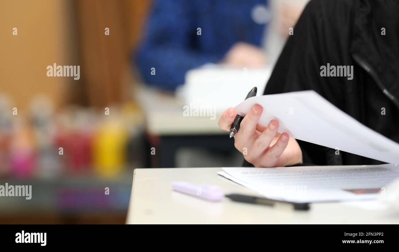 Un primo piano gli studenti isolati tengono una mano con una penna che controlla le loro risposte durante la lezione, l'esame o il tempo della lezione a scuola. Colori brillanti e secondo studente b Foto Stock