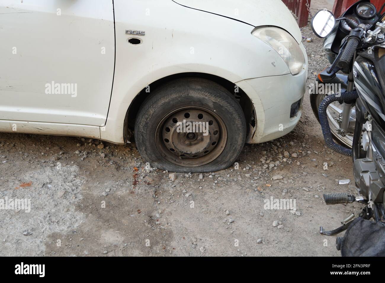 Perdita di pneumatici, ruota di primo piano di vecchia auto d'epoca bianca. Ruota per auto con pneumatico sgonfio su strada. Sgonfio il pneumatico di una vecchia vettura accanto a una motocicletta. - Udaipur i Foto Stock
