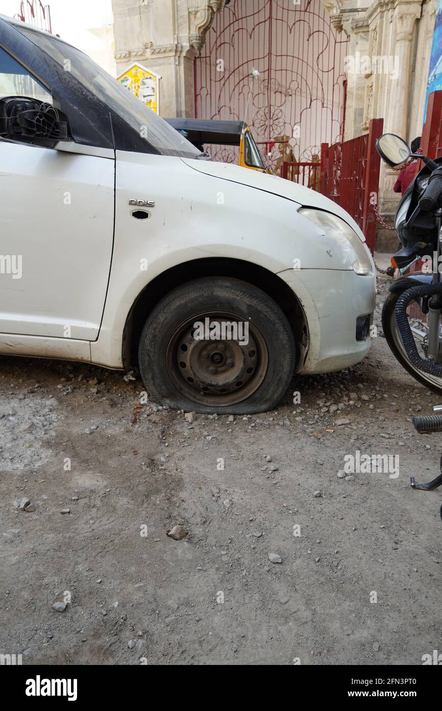 Perdita di pneumatici, ruota di primo piano di vecchia auto d'epoca bianca. Ruota per auto con pneumatico sgonfio su strada. Sgonfio il pneumatico di una vecchia vettura accanto a una motocicletta. - Udaipur i Foto Stock
