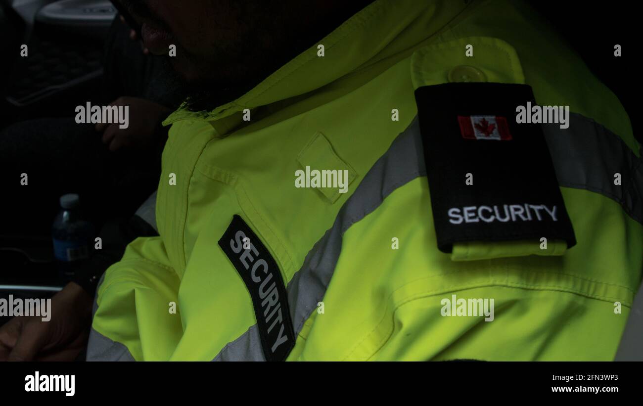 Primo piano di una guardia di sicurezza in uniforme in piedi e in attesa del suo ordine in una vettura di pattuglia Foto Stock