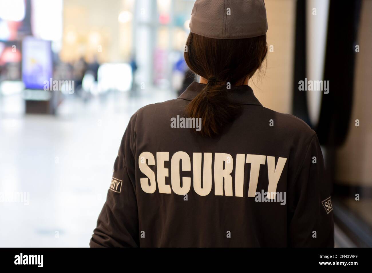 Vista posteriore di una guardia di sicurezza femminile con pattugliamento uniforme in una zona residenziale Foto Stock