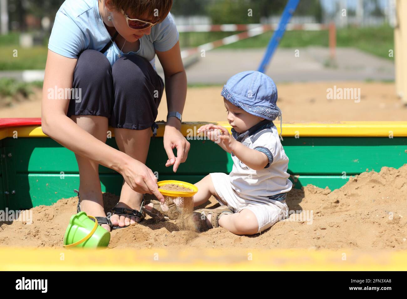 Madre e suo figlio setacciarono la sabbia in un sandbox Foto Stock