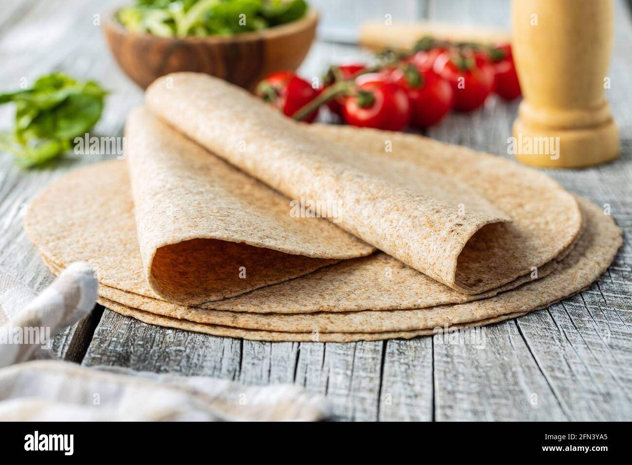 Tortilla a grani interi avvolge su tavola di legno. Foto Stock