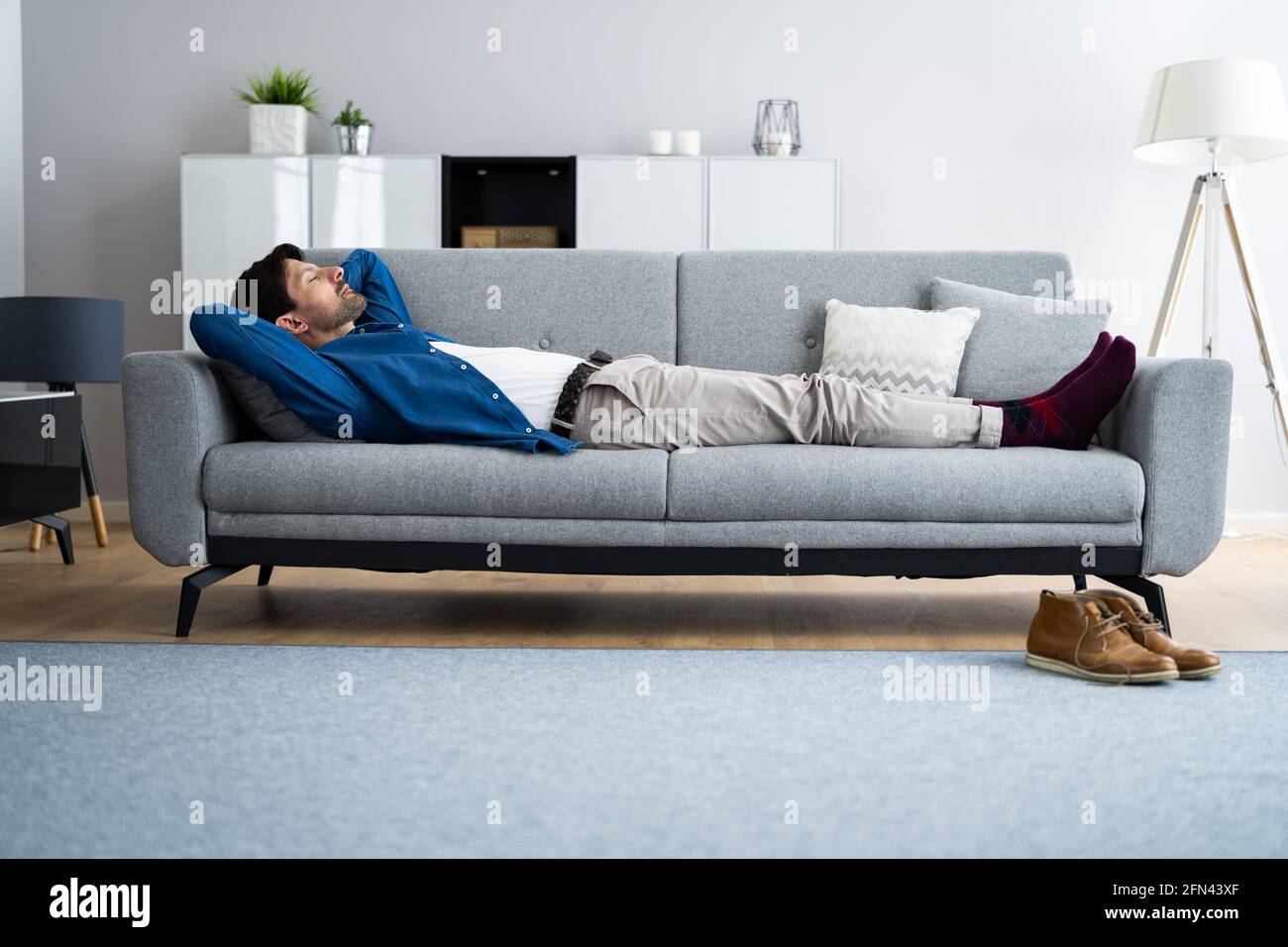 Russare addormentando l'uomo sul divano nel soggiorno Foto Stock