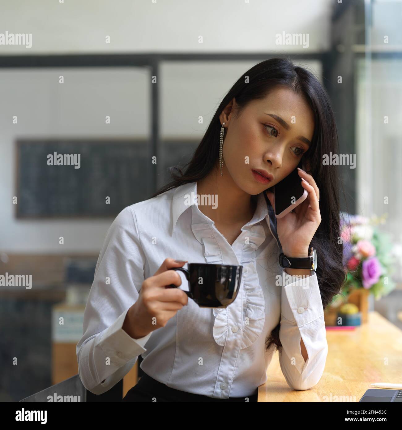 Ritratto di donna che parla al telefono mentre beve caffè in cafa Foto Stock