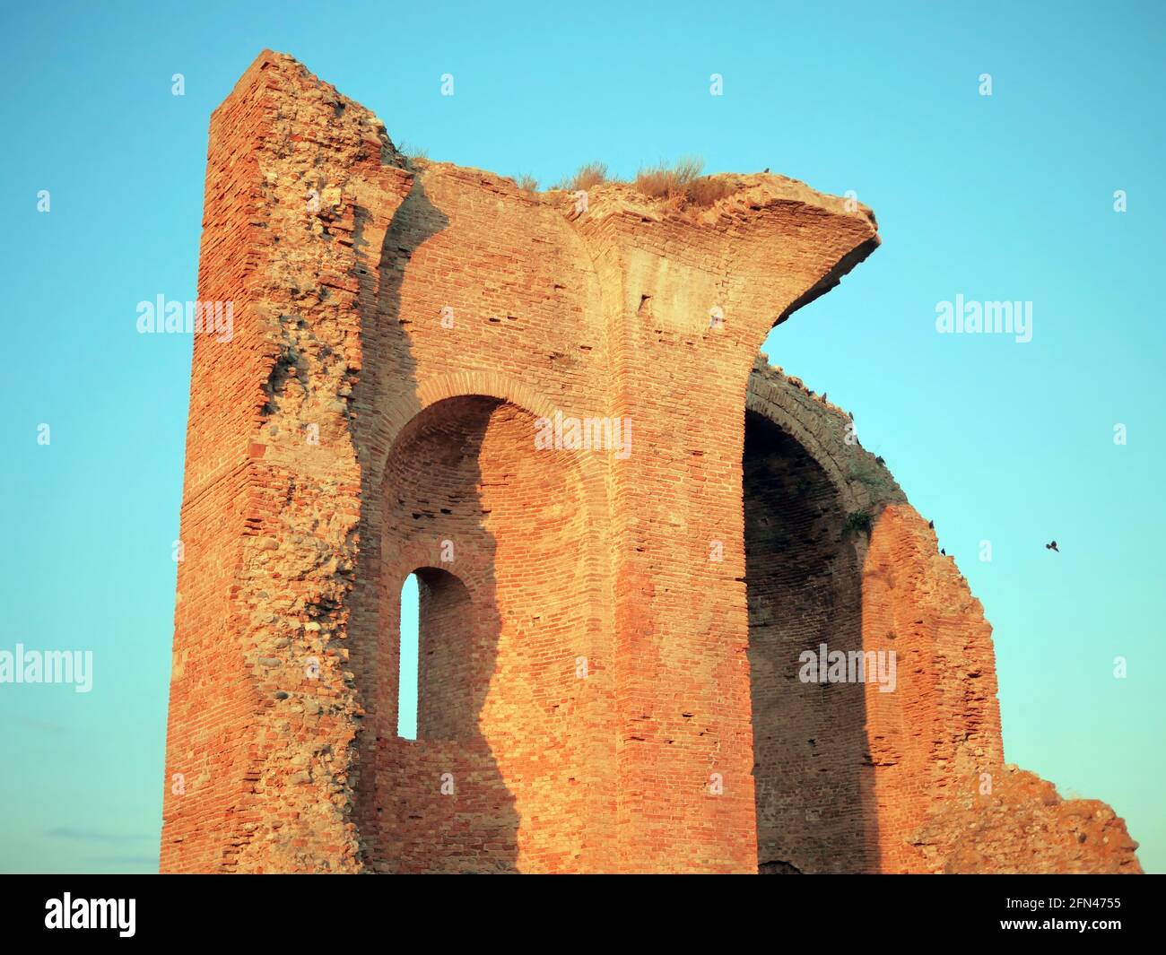 Rovine di un'antica cattedrale medievale illuminata dal sole tramontante. Colori complementari al crepuscolo. Foto Stock