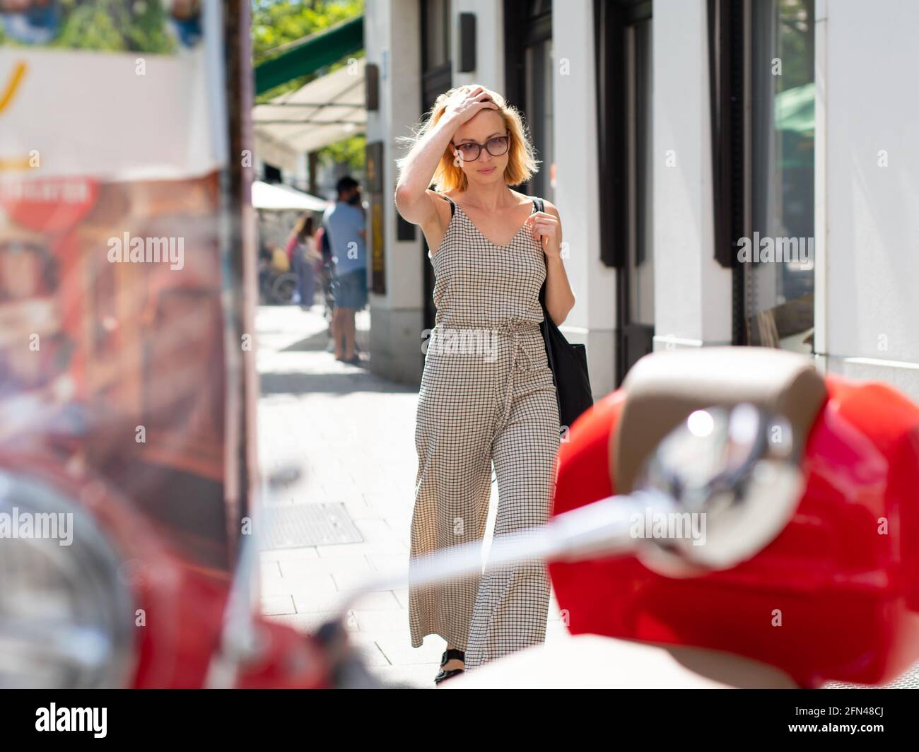 Ritratto di bella donna giovane e sfavola che cammina sul marciapiede della strada. Foto Stock