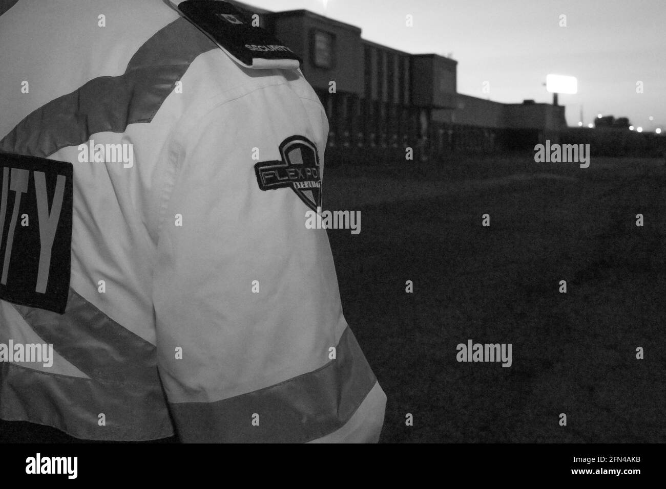 Una vista posteriore di una guardia di sicurezza che guarda giù per la strada e il tramonto. Foto Stock