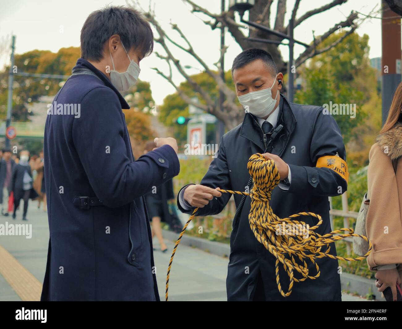 Due guide giapponesi dispongono di una corda colorata. Due uomini asiatici con maschere organizzano il percorso per i turisti. Stile di vita e abilità manuali. Foto Stock