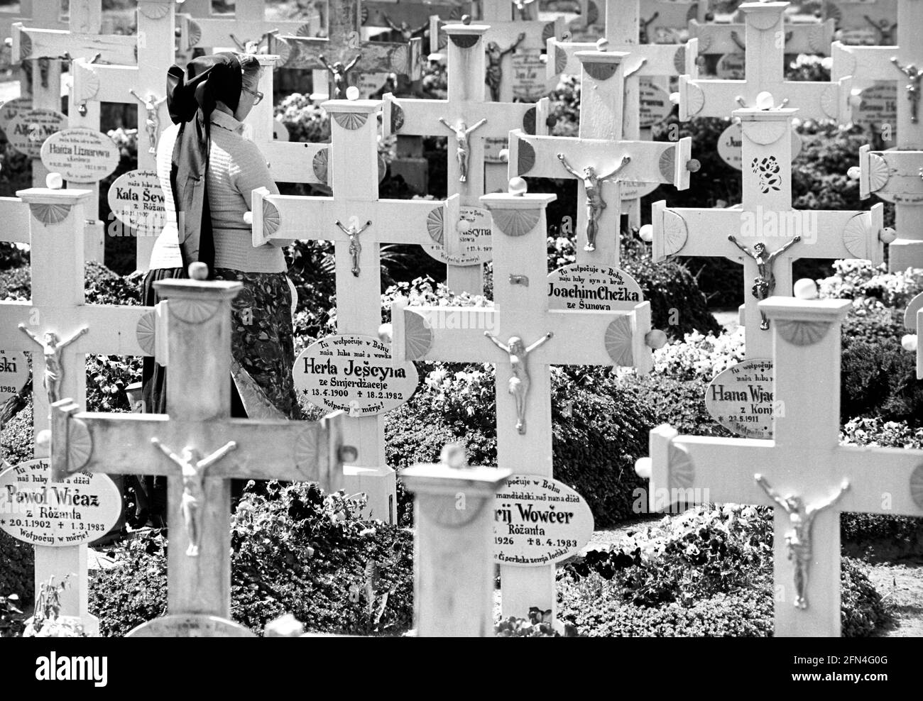 Una donna in costume sorbiano visita un cimitero sorbiano a Lusazia con una serie di croci bianche uniformi una tomba. 04.05.1990 - Christoph Keller Foto Stock