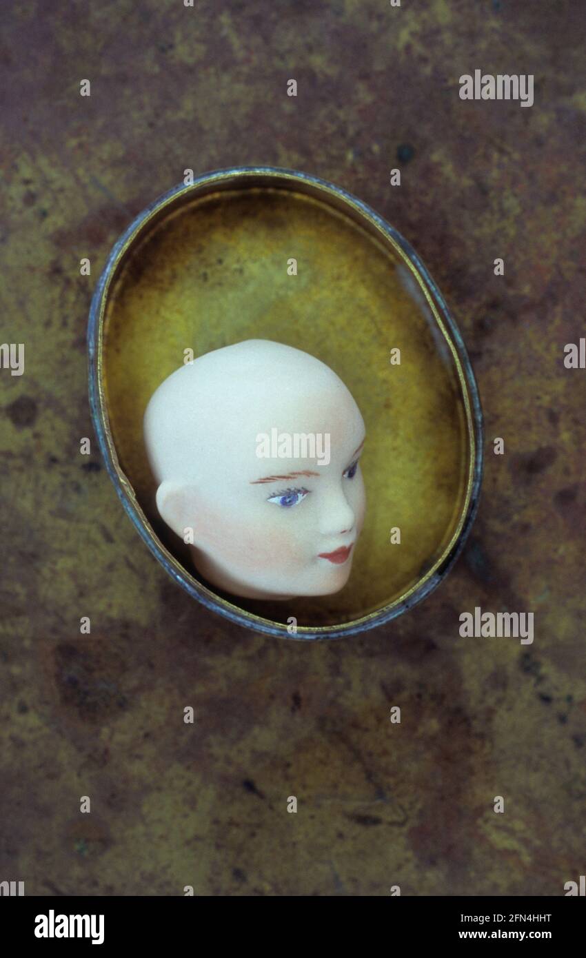 Piccola testa bisque di bambola adulta 1940 sdraiata in un contenitore di ottone Foto Stock