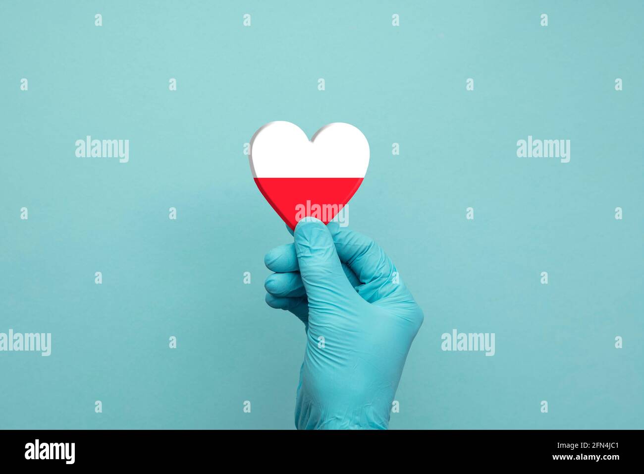 Mani che indossano guanti chirurgici protettivi che tengono il cuore della bandiera della Polonia Foto Stock