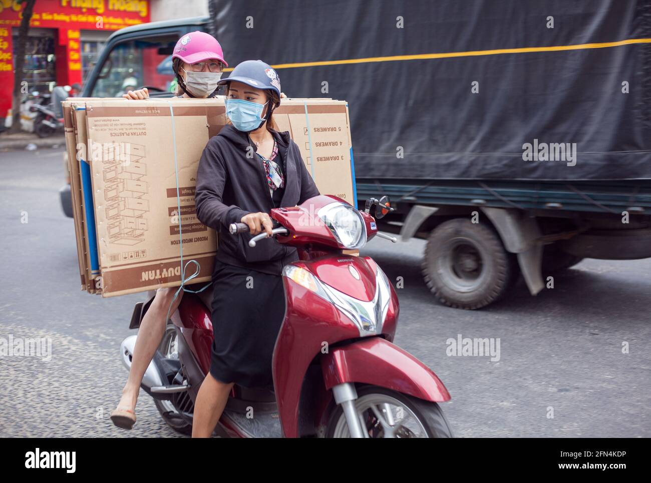 Scooter da guida femminile vietnamita sovraccarico di ingombranti prodotti per la casa, da Nang, Vietnam Foto Stock