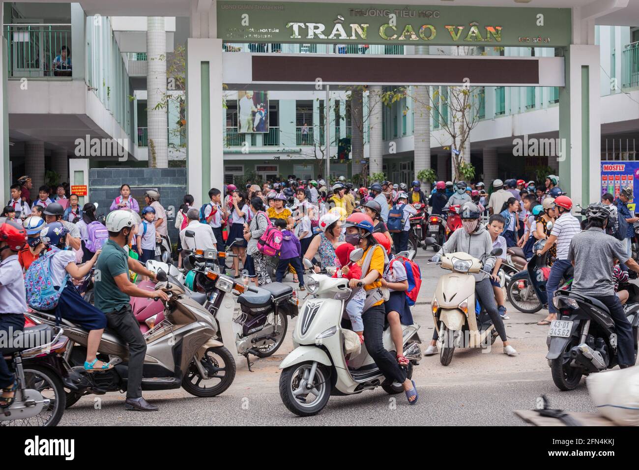 Area congestionata come molti genitori arrivano alle porte della scuola su moto e scooter nel corso della scuola pomeridiana, da Nang, Vietnam Foto Stock