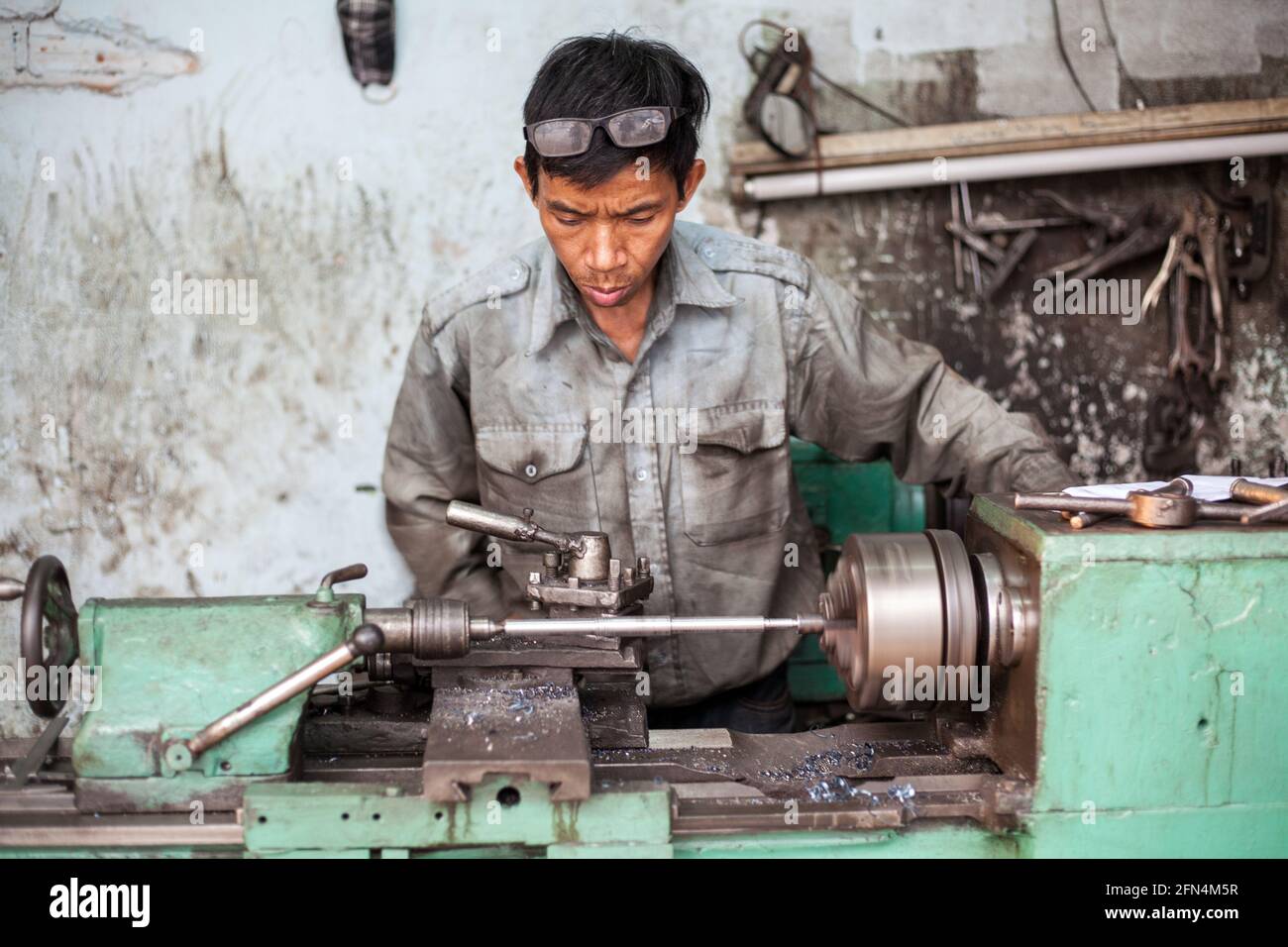 Ingegnere vietnamita che lavora sul tornio di filatura in strada (girato a f/2.5 apertura con testa e tornio in fuoco), da Nang, Vietnam Foto Stock