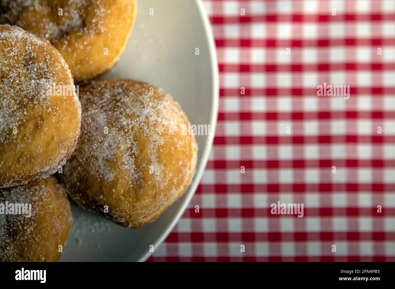 Vista dall'alto verso il basso di Jam Donuts su un piatto con uno sfondo rosso a forma di gingham e uno spazio per la copia Foto Stock