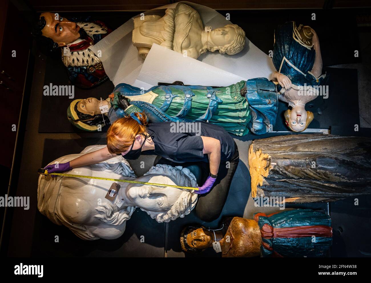 Il responsabile tecnico Elle Dunthorne misura i capi figuranti della nave prima del trasporto al Museo Marittimo di Hull, poiché circa 50,000 oggetti vengono imballati e rimossi dall'edificio classificato di grado II prima di un rinnovo di £12 m. Data immagine: Venerdì 14 maggio 2021. Foto Stock