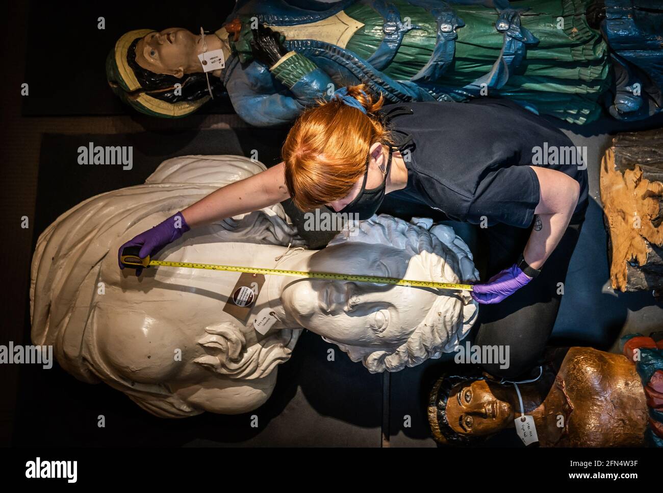 Il responsabile tecnico Elle Dunthorne misura i capi figuranti della nave prima del trasporto al Museo Marittimo di Hull, poiché circa 50,000 oggetti vengono imballati e rimossi dall'edificio classificato di grado II prima di un rinnovo di £12 m. Data immagine: Venerdì 14 maggio 2021. Foto Stock