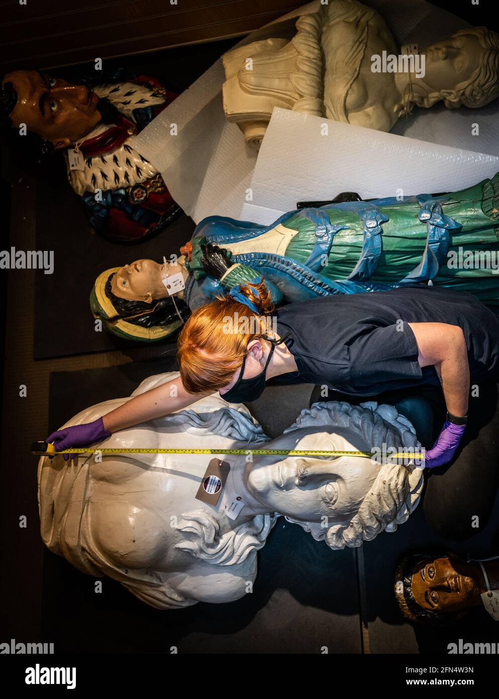 Il responsabile tecnico Elle Dunthorne misura i capi figuranti della nave prima del trasporto al Museo Marittimo di Hull, poiché circa 50,000 oggetti vengono imballati e rimossi dall'edificio classificato di grado II prima di un rinnovo di £12 m. Data immagine: Venerdì 14 maggio 2021. Foto Stock