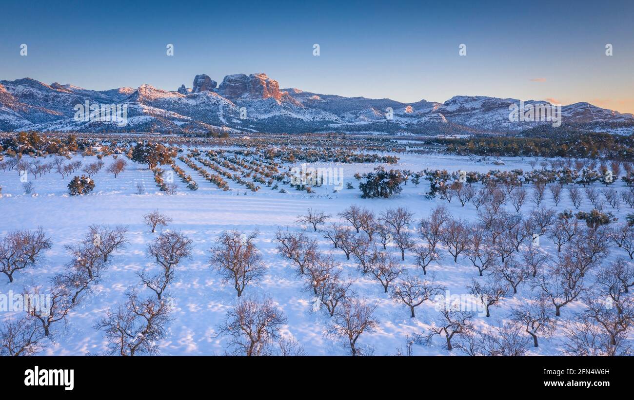 Vista aerea dei porti di Els / la catena montuosa di Los Puertos e dintorni del villaggio di Horta de Sant Joan in un tramonto invernale innevato (Tarragona, Spagna) Foto Stock