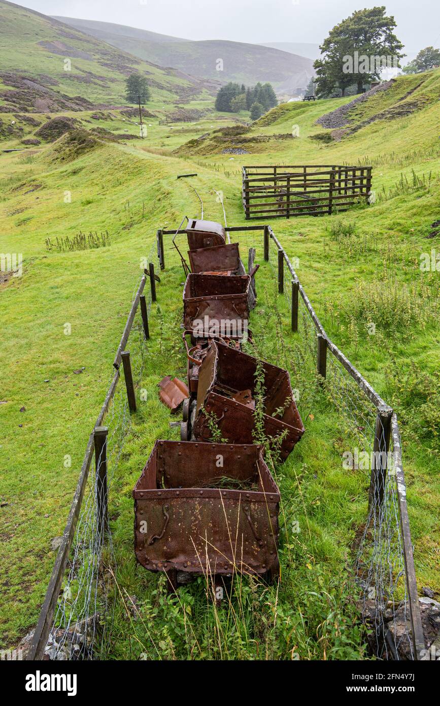 Vecchi camion minerari arrugginiscono all'ingresso di una vecchia miniera di piombo storica a Wanlockhead in Scozia. Foto Stock