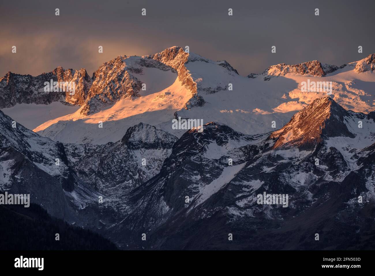 L'alba rossa sul massiccio innevato delle Maladetas e la vetta dell'Aneto. Vista dalla valle di Varradòs in autunno (Valle di Aran, Catalogna, Spagna) Foto Stock