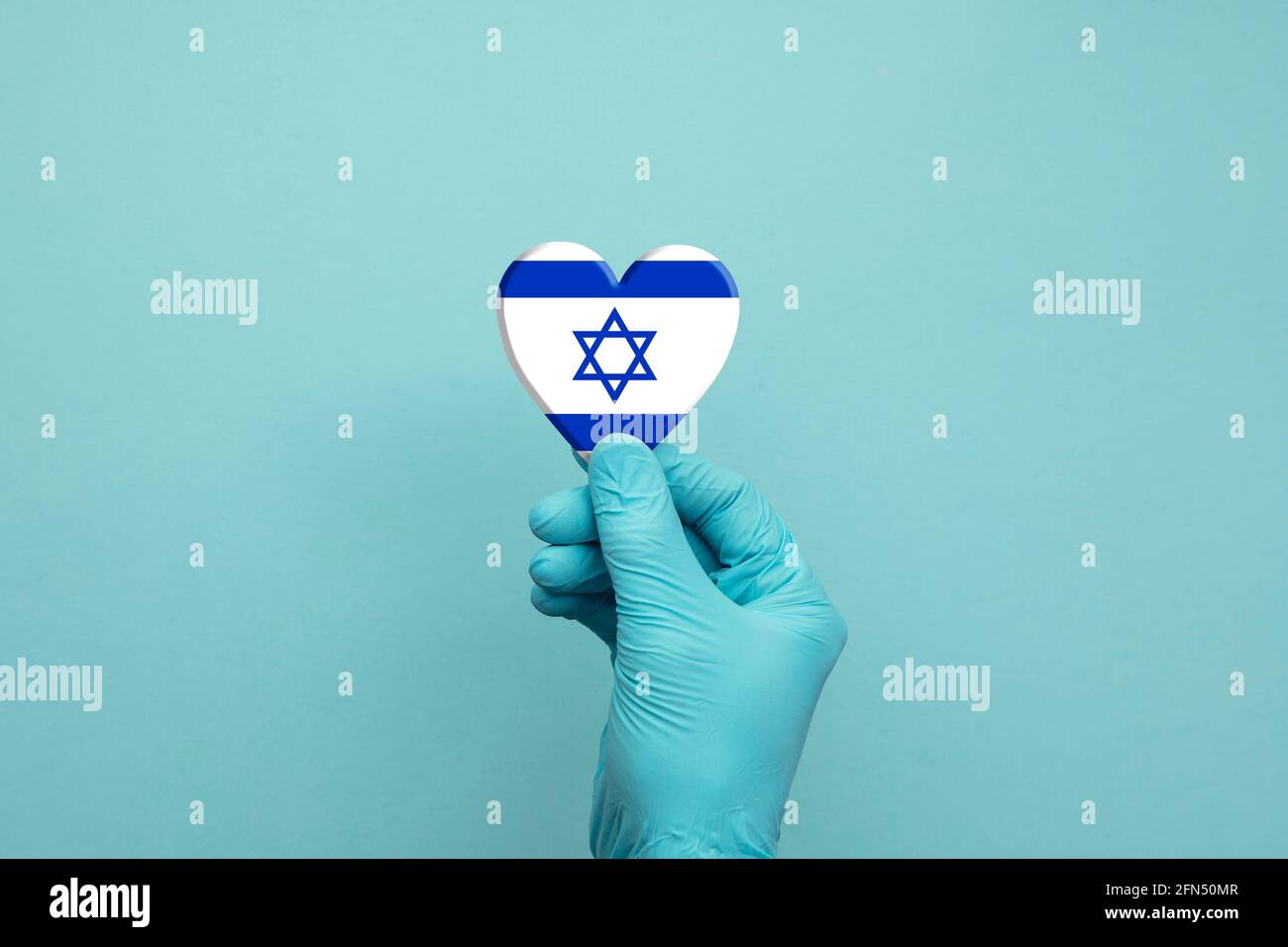 Mani che indossano guanti chirurgici protettivi che tengono Israele bandiera cuore Foto Stock