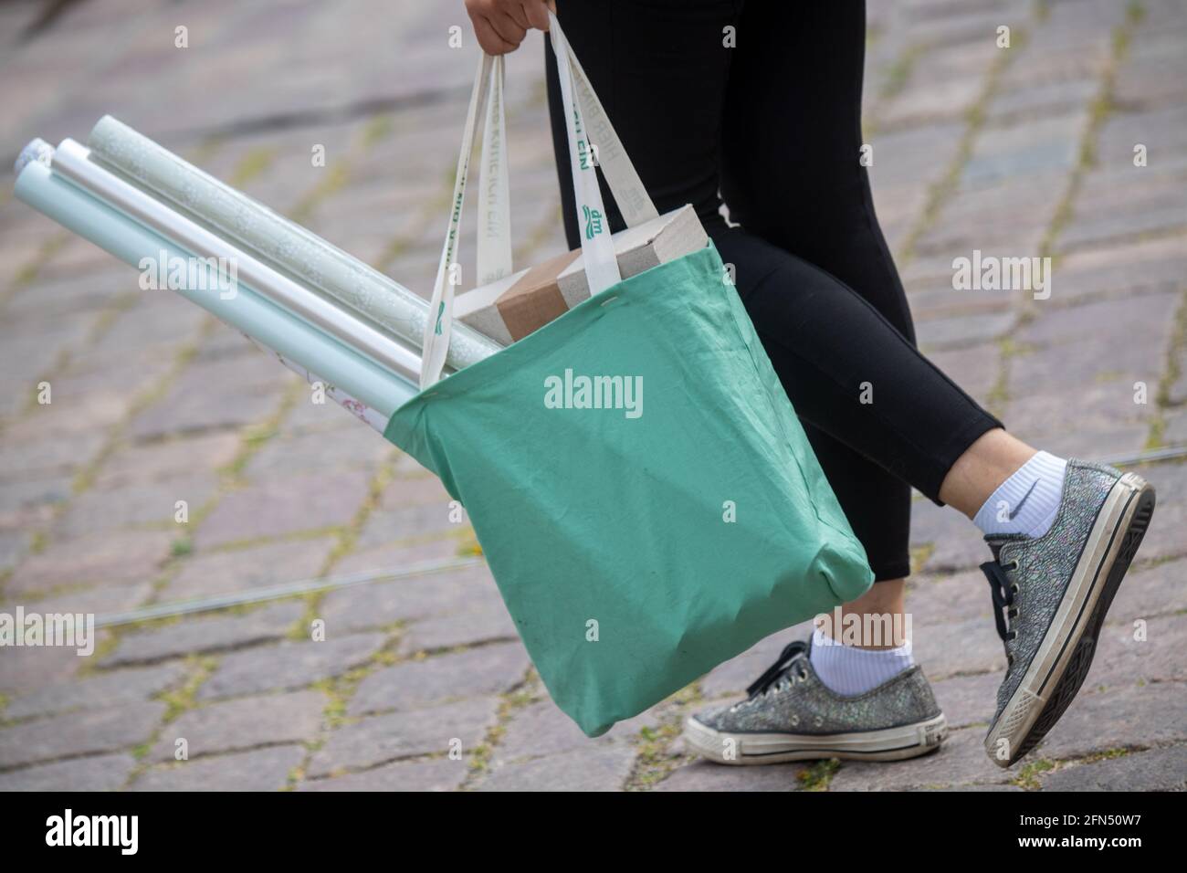 Stralsund, Germania. 14 maggio 2021. Una persona porta una borsa per lo shopping sulla strada dello shopping e zona pedonale Ossenreyer Street sono numerosi passanti, maschere sono obbligatorie. Retail nel distretto di Vorpommern-Rügen riapre, è il primo distretto di Meclemburgo-Pomerania occidentale, in cui i negozi sono autorizzati ad aprire completamente di nuovo, perché l'incidenza di sette giorni vi è già al di sotto di 50. Credit: Stefan Sauer/dpa/Alamy Live News Foto Stock